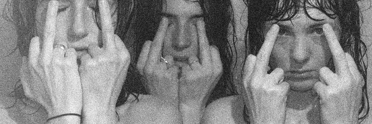 Three people cover their faces by holding their raised middle fingers before their faces in a black-and-white, grainy image.