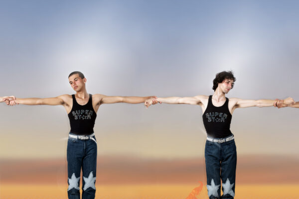 Twee mensen in sprong met zwarte tanktops en jeans met sterren, vlammen aan voeten, tegen een kleurverloophemel.